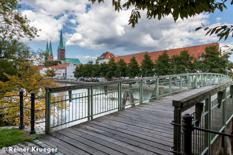 IMG_5743.jpg - Fußgängerbrücke über die Obertrave, dahinter Petrikirche (ein Turm) und Marienkirche (zwei Türme)